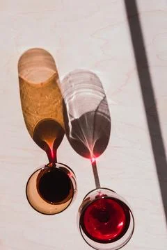 2 glasses of red wine casting long shadows against wooden table Stock Photos
