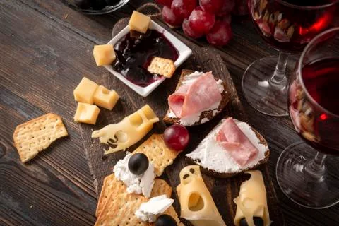 2 glasses of red wine ,  tapas, appetizer,  slices of cheese, cracker, ham, j Stock Photos