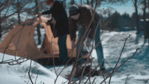 2 guys are banging a fire near the tent Stock Footage 87586271