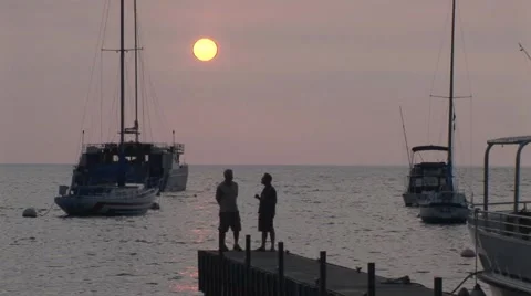 2 Guys Talking at Sunset at the End of Pier wtih Sun Stock Footage 5240294