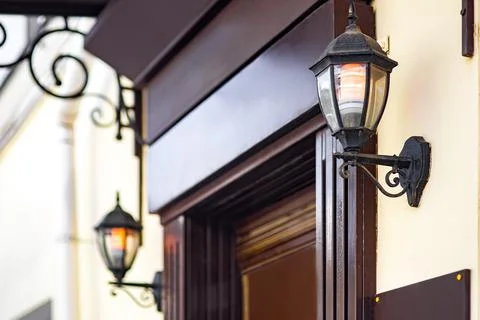 2 iron retro lanterns on the wall of the facade of the building. Stock Photos