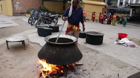 2-man-cooking-open-fire-large-pot-Hyderabad-India Stock Footage 93348210