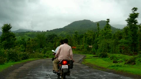 2 men on bike driving on empty wet Monsoon cloudy hill Road Mahabaleshwar India Stock Footage 155983246