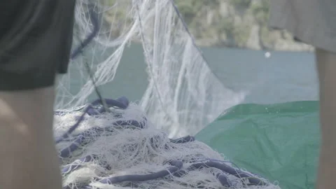 2 men cast out a net on the back of a boat Stock Footage 232304526