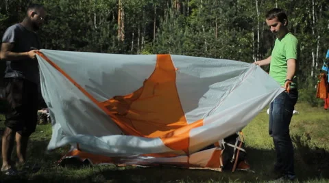 2 men stacked orange tent. Summer sunny day in the forest Stock Footage 64486380