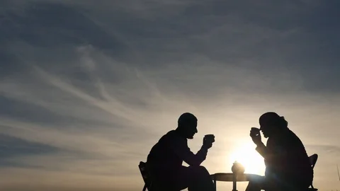 2 men at table drink tea silhouettes outdoors with beautiful sky Stock Footage 88708207