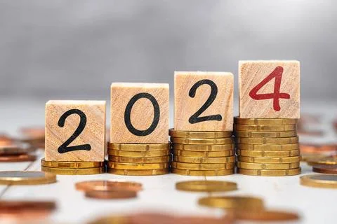 2 November 2023: Die Jahreszahl 2024 auf Holzwürfeln auf Münzgeld Stapel.. Stock Photos