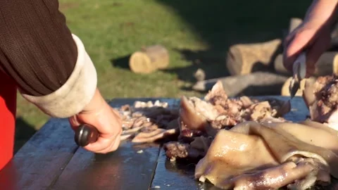 2 people with faces not visible cutting pork with knives on an outdoor tabl.. Stock Footage 252326887