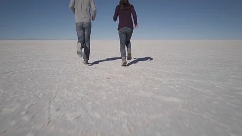 2 people run in slow motion on the salt flats in the Salar de Uyuni Stock Footage 83404741