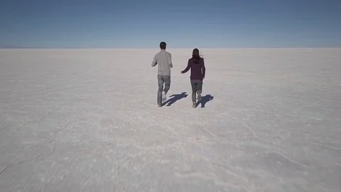 2 people run in slow motion on the salt flats in the Salar de Uyuni Stock Footage 83404744