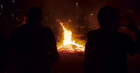 2 people silhouette from  back looking a bonfire in the night slowmotion Stock Footage 277351614