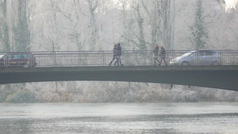2 people walking over bridge in winter creating reflections Video stock 147996882