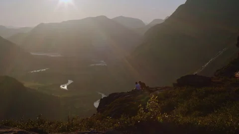 2 persons sitting on a scenic mountain at sunset Stock Footage 265098257