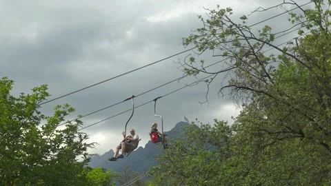 2 persons with waving hand crossing in chairlift from Tyrol Village to Merano in Stock Footage 228283949
