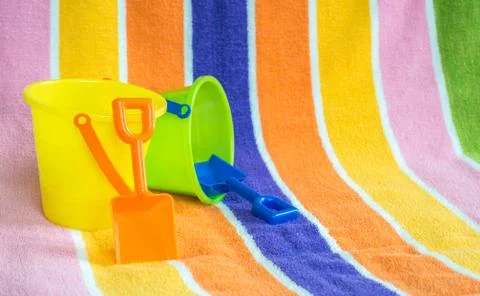 2 plastic sand pails and shovels on a striped beach towel Stock Photos