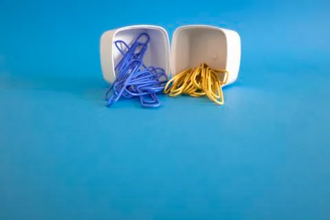 2 plastic white boxes in a row. There are colored paper clips inside. Stock Photos