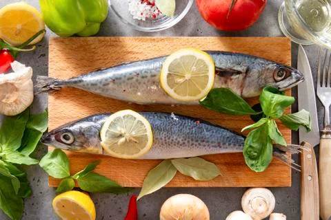 2 raw mackerel fish with lemon slices, tomato, Basil, spices ,  mushrooms, oi Stock Photos