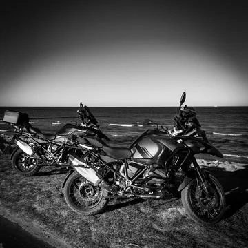 2 off road motorcycles standing side by side by the sea Stock Photos