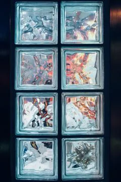 2 rows of glass decorative blocks on a metal wall. Colored objects are refracted Stock Photos