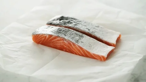 2 Salmon fillets on grease-proof paper on marble. Stock Footage 92144523