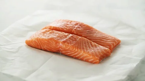 2 Salmon fillets on grease-proof paper on marble. Stock Footage 92144785