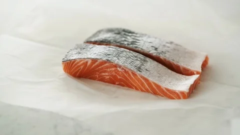 2 Salmon fillets opened from grease-proof paper on marble. Stock Footage 92144027