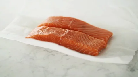 2 Salmon fillets opened from grease-proof paper on marble. Stock Footage 92144601