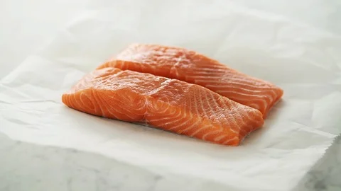 2 Salmon fillets opened from grease-proof paper on marble. Stock Footage 92144700