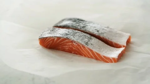 2 Salmon fillets slowly opened from grease-proof paper on marble. Stock Footage 92144033