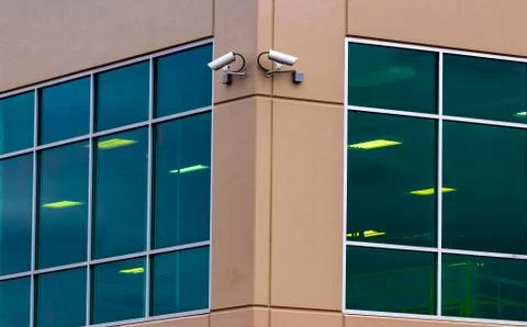 2 security cameras on the side of a building with window Stock Photos
