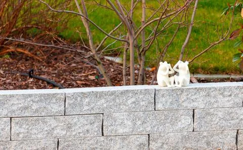 2 small white frog figures sitting on a wall Stock Photos