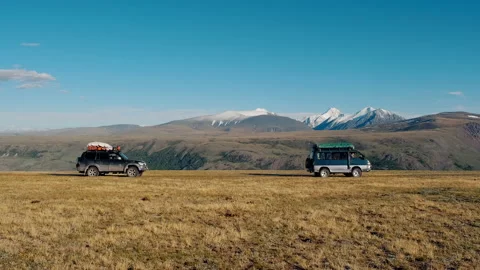 2 SUVs cross an empty plain against the backdrop of a mountainous landscape Stock Footage 140898285