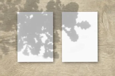 2 vertical sheets of textured white paper on wooden table background. Mockup  Illustrazione stock