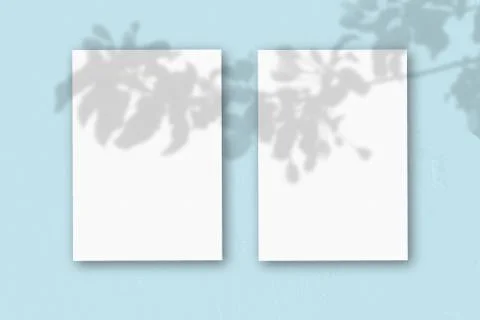 2 vertical sheets of textured white paper on soft blue table background. Mock Stock Illustration