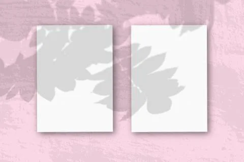 2 vertical sheets of textured white paper on soft pink table background. Mock Stock Photos