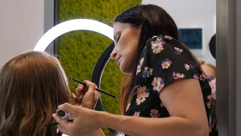 2 Working process master stylist doing makeup for a young woman in beauty sal Stock Footage 92740235