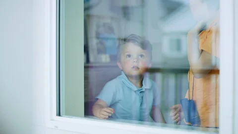2 year old boy looks up at something in awe outside the window in slow motion 스톡 동영상 127547020