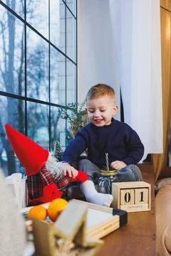A 2-year-old boy sits on the windowsill in the new year. New Year's atmosph.. Stock Photos