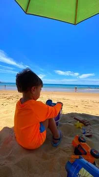 2 year old child playing in the sand on the beach. Stock Photos