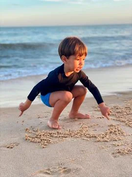 2 year old child playing in the sand on the beach. Stock Photos