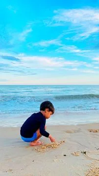 2 year old child playing in the sand on the beach. Stock Photos