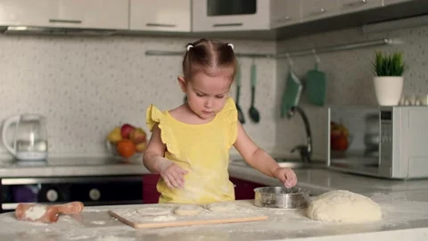 A 2-year-old child prepares pastries from dough and flour in the kitchen at the Video stock 188201000