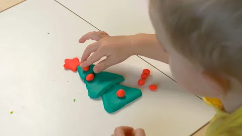 A 2-year-old preschool kid  making christmas tree from modeling clay (compound) Stock Footage 99414799