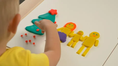 A 2-year-old preschool kid  making christmas tree from modeling clay (compound) Vídeo Stock 99451409