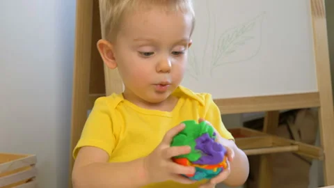 A 2-year-old preschool kid  making christmas tree from modeling clay (compound) Stockbeeldmateriaal 99525505