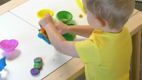 A 2-year-old preschool kid  making christmas tree from modeling clay (compound) Stockbeeldmateriaal 99526416