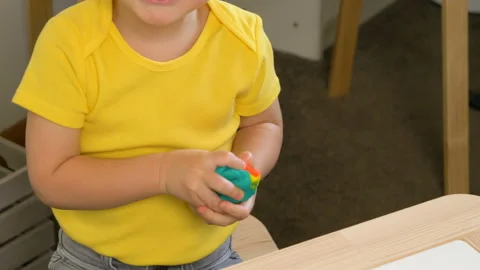 A 2-year-old preschool kid  making christmas tree from modeling clay (compound) Видео 99530259