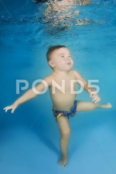 2 years boy learning to swim underwater in the pool Stock Photos