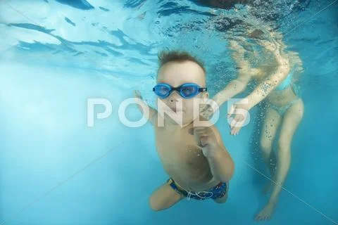 2 years boy learning to swim underwater in the pool Stock Photos