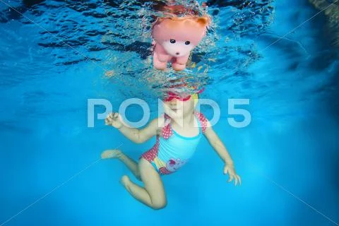 2 years girl with a toy learning to swim underwater in the pool, Stock Photos